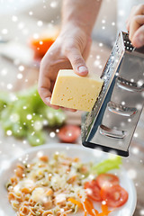 Image showing close up of male hands with grater grating cheese