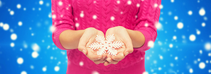 Image showing close up of woman in sweater holding snowflake