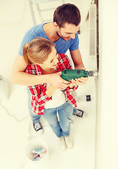 Image showing smiling couple drilling hole in wall at home