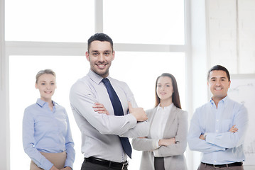 Image showing smiling businessman in office with team on back