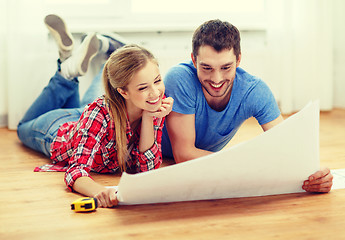 Image showing smiling couple looking at blueprint at home