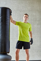 Image showing man with boxing gloves and punching bag in gym