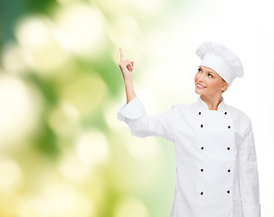 Image showing smiling female chef pointing finger to something