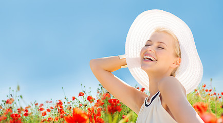 Image showing smiling young woman in straw hat on poppy field