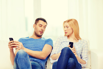 Image showing concentrated couple with smartphones at home