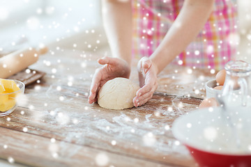 Image showing close up of female hands kneading dough at home