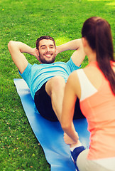 Image showing smiling man doing exercises on mat outdoors