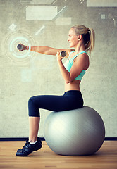 Image showing smiling woman with dumbbells and exercise ball