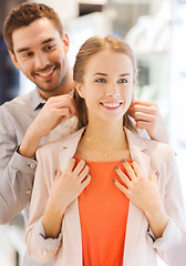 Image showing couple trying golden pendant on at jewelry store