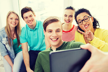 Image showing smiling students making picture with tablet pc