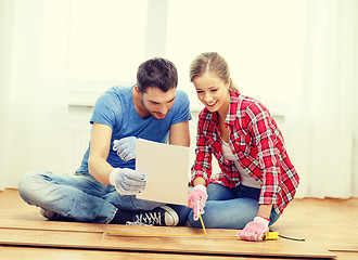 Image showing smiling couple measuring wood flooring