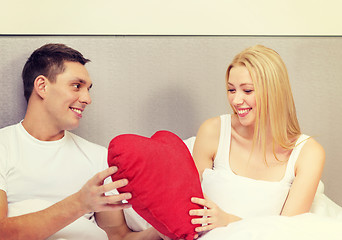 Image showing smiling couple in bed with red heart shape pillow