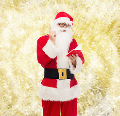 Image showing man in costume of santa claus with notepad