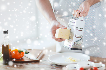 Image showing close up of male hands with grater grating cheese