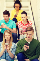 Image showing busy students with smartphones sitting on stairs