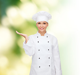 Image showing smiling female chef holding something on hand