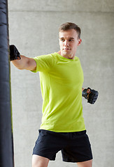 Image showing young man in gloves boxing with punching bag