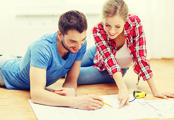 Image showing smiling couple looking at blueprint at home