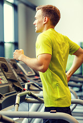 Image showing smiling man exercising on treadmill in gym