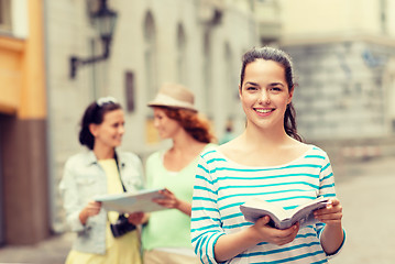 Image showing smiling teenage girls with city guides and camera