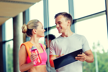 Image showing smiling young woman with personal trainer in gym