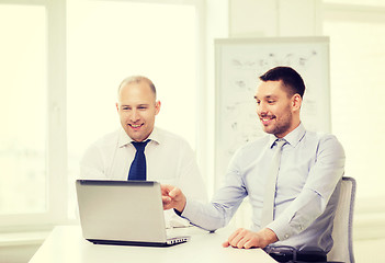 Image showing two smiling businessmen with laptop in office