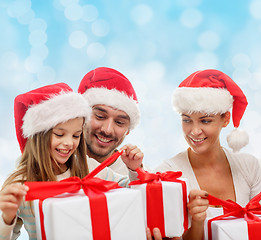 Image showing happy family in santa hats sitting with gift boxes