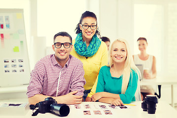Image showing smiling team with printed photos working in office