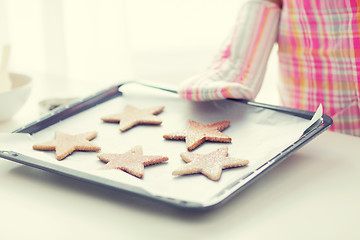 Image showing close up of woman with cookies on oven tray