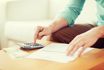 Image showing close up of man counting money and making notes