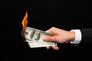 Image showing close up of male hand holding burning dollar money