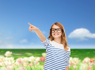 Image showing cute little girl in eyeglasses pointing in the air