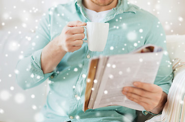 Image showing close up of man with magazine drinking from cup