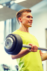 Image showing smiling man doing exercise with barbell in gym