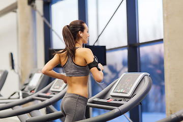 Image showing woman with earphones exercising on treadmill