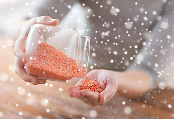 Image showing close up of woman emptying jar with red lentils