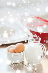 Image showing close up of milk jug, eggs, whisk and flour