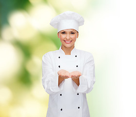 Image showing smiling female chef holding something on hands