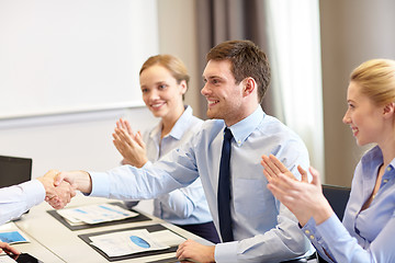 Image showing smiling business team shaking hands in office