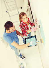 Image showing smiling couple painting wall at home