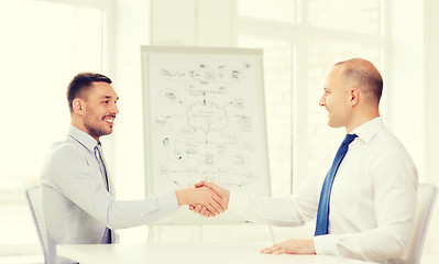 Image showing two smiling businessmen shaking hands in office