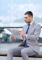 Image showing young serious businessman newspaper outdoors