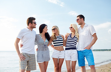 Image showing smiling friends in sunglasses talking on beach