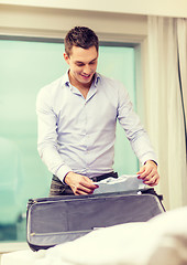 Image showing businessman packing things in suitcase