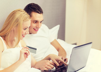 Image showing couple in bed with laptop computer and credit card