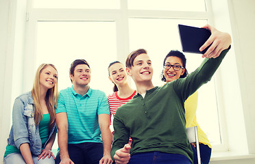 Image showing smiling students making picture with tablet pc