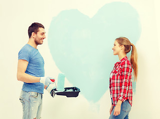 Image showing smiling couple painting big heart on wall