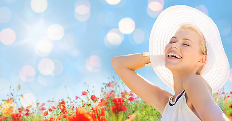 Image showing smiling young woman in straw hat on poppy field