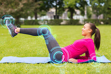 Image showing smiling woman doing exercises on mat outdoors