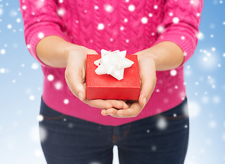 Image showing close up of woman in pink sweater holding gift box